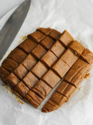 date caramels after being sliced into small squares on parchment paper.