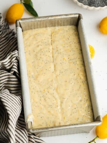 lemon poppy seed cake batter in a lined loaf pan before baking.