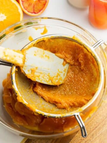 pressing orange curd through a fine mesh sieve with a spatula.