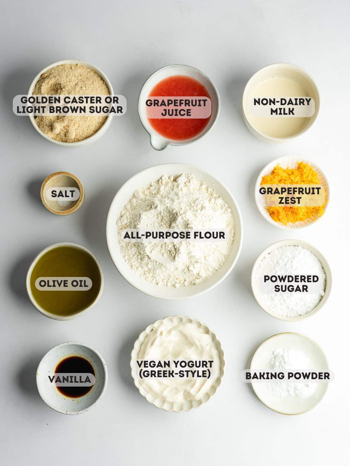 ingredients for vegan grapefruit cake measured out in bowls on a white surface.
