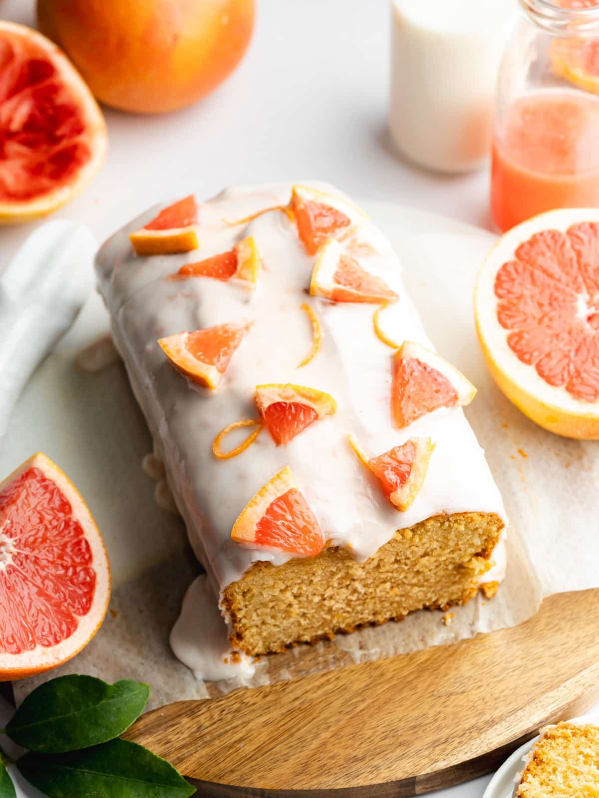 a pink grapefruit loaf cake with thick icing and grapefruit segments on top.