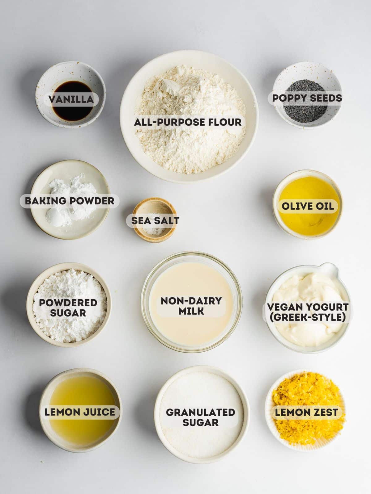 ingredients for lemon poppyseed cake measured out in bowls on a gray surface.
