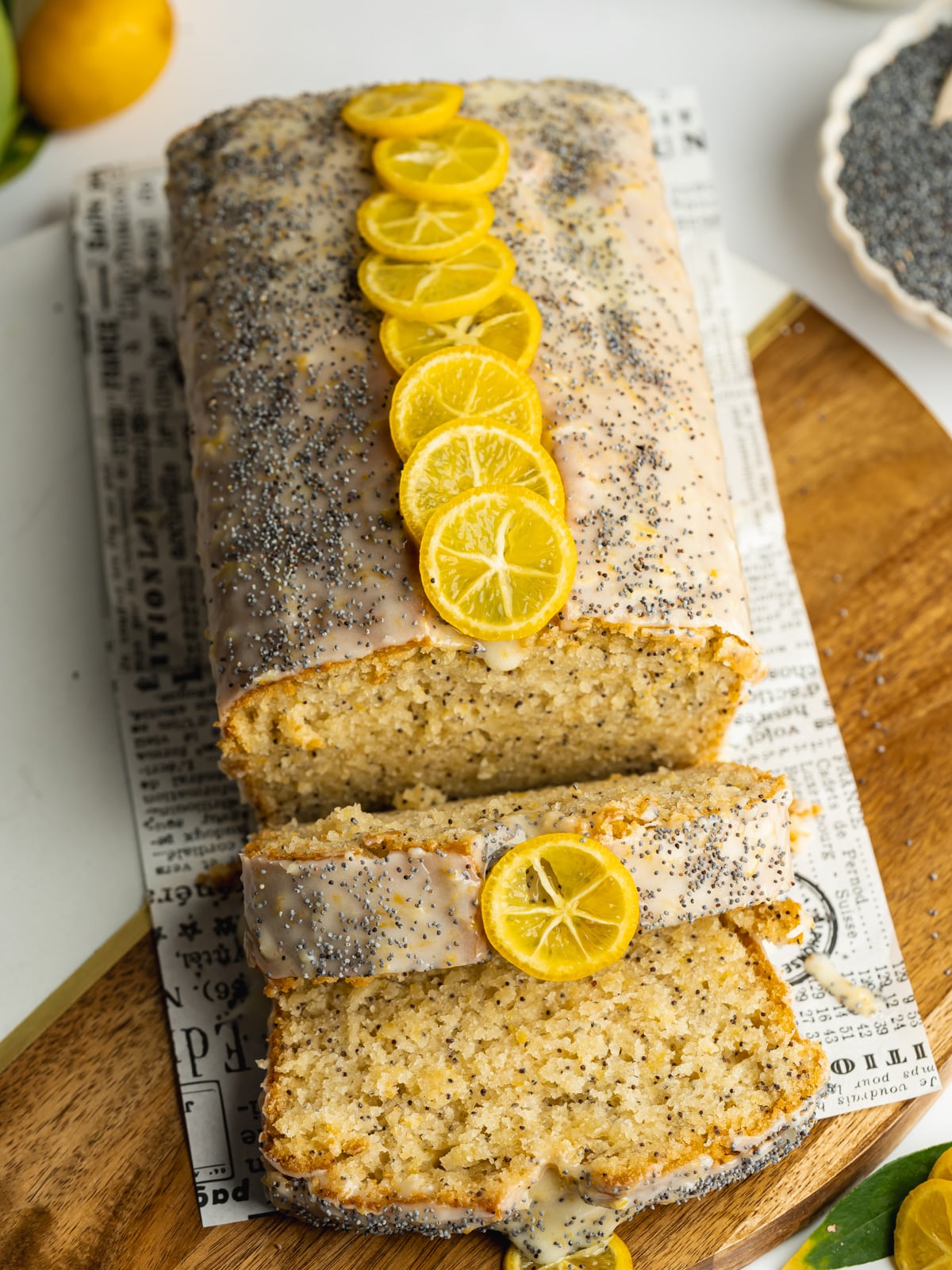 a lemon and poppy seed loaf on parchment paper with 2 slices cut from it.