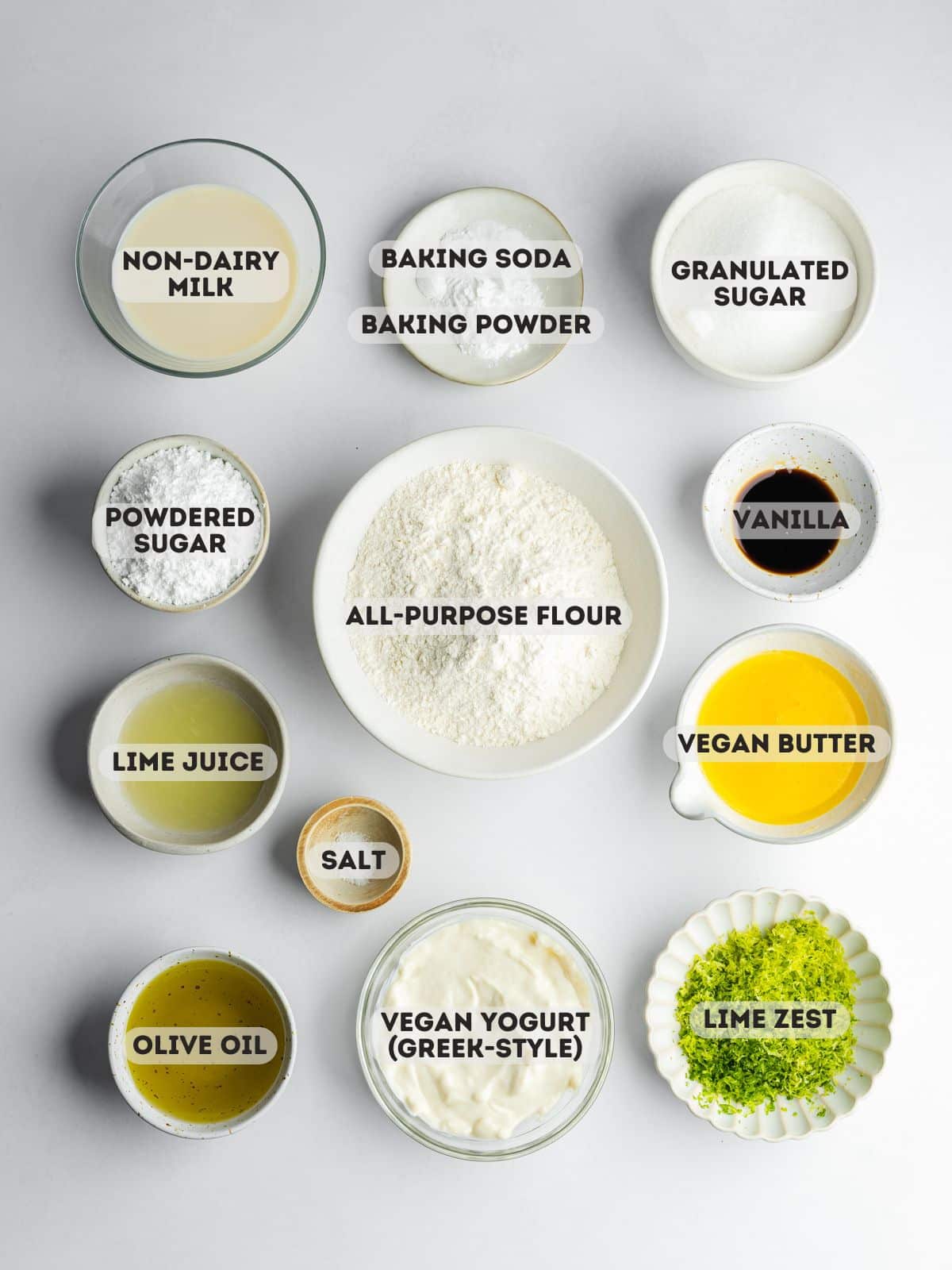 ingredients for key lime loaf cake measured out in bowls on a gray surface.