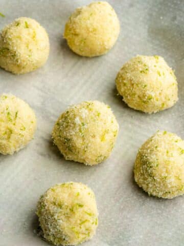 lime sugar cookie dough balls on a lined sheet before going into the freezer to rest.