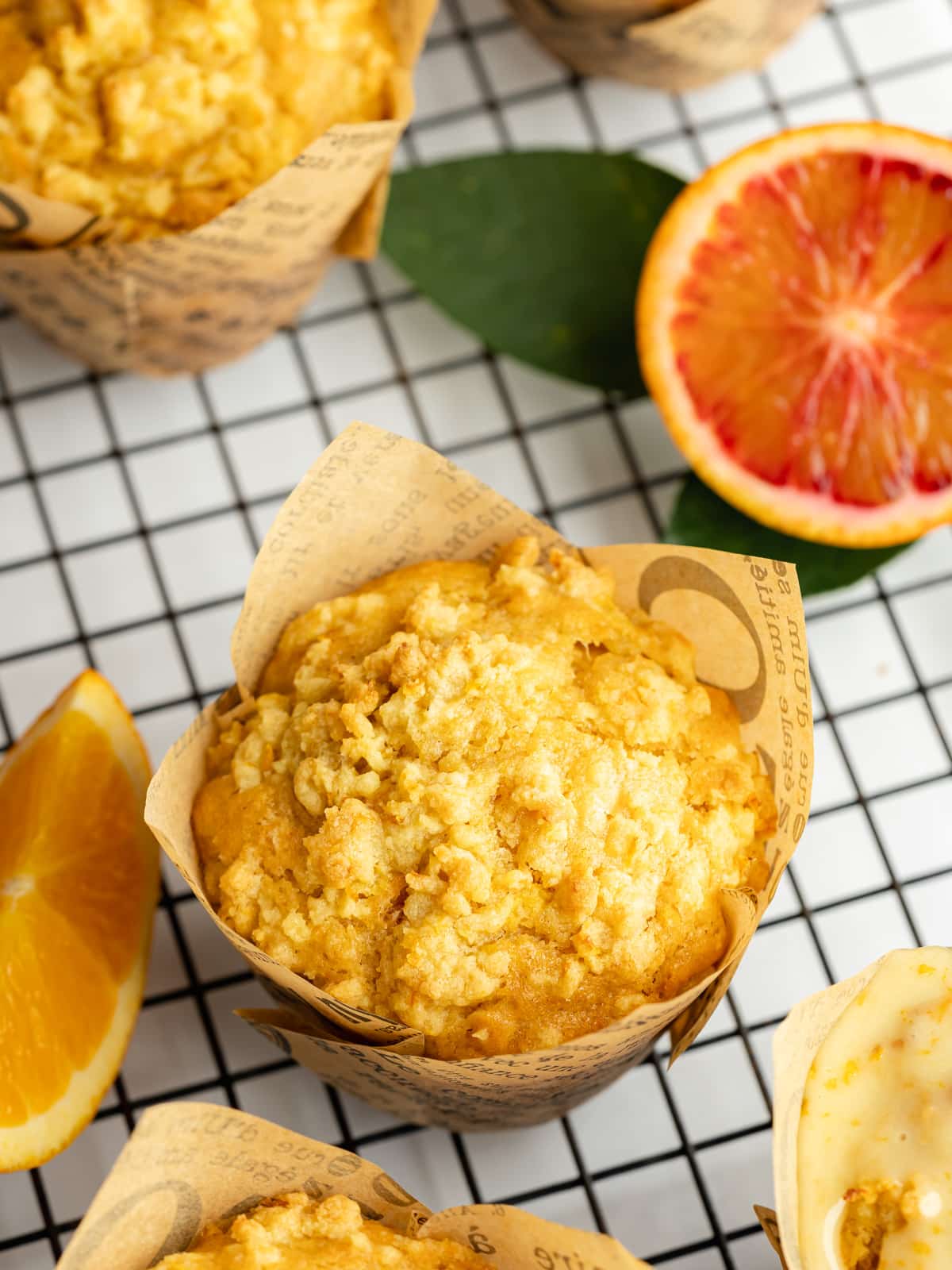 orange muffins with crumble topping on a wire cooling rack.