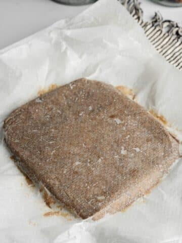 date caramel paste rolled into a square between 2 sheets of parchment paper.