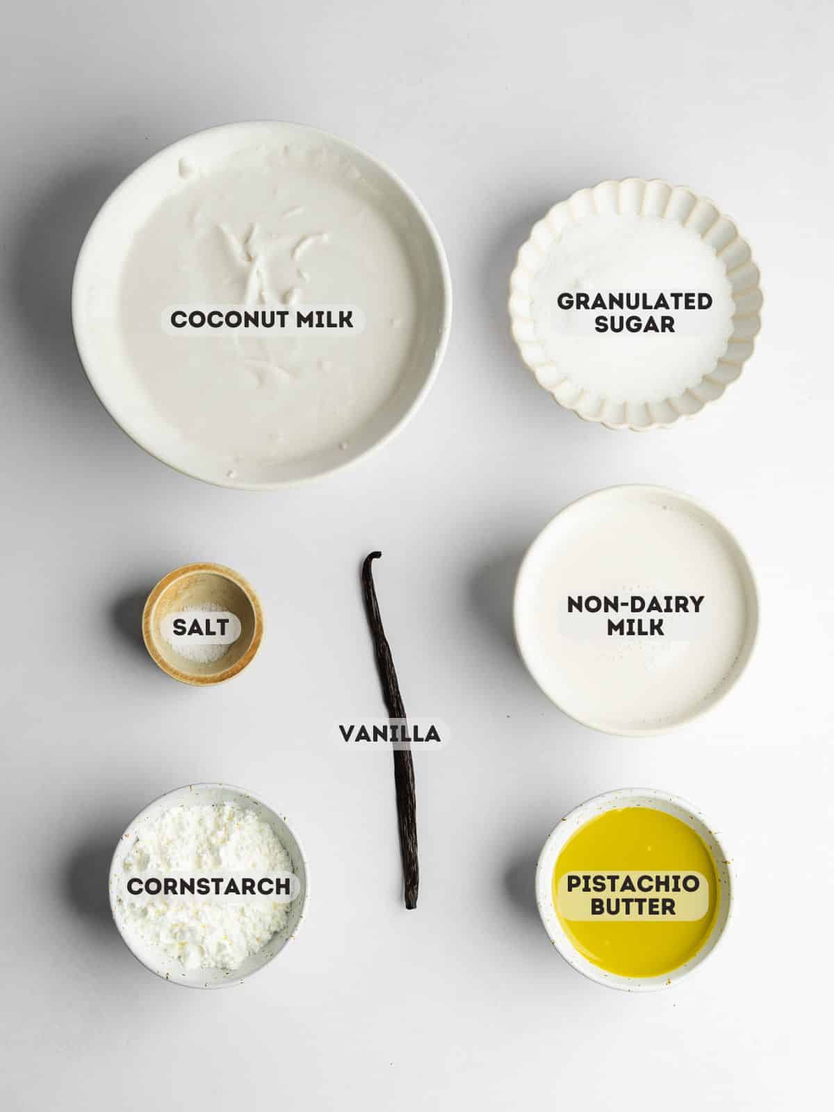 ingredients for pistachio creme brulee measured out in bowls on a white surface.