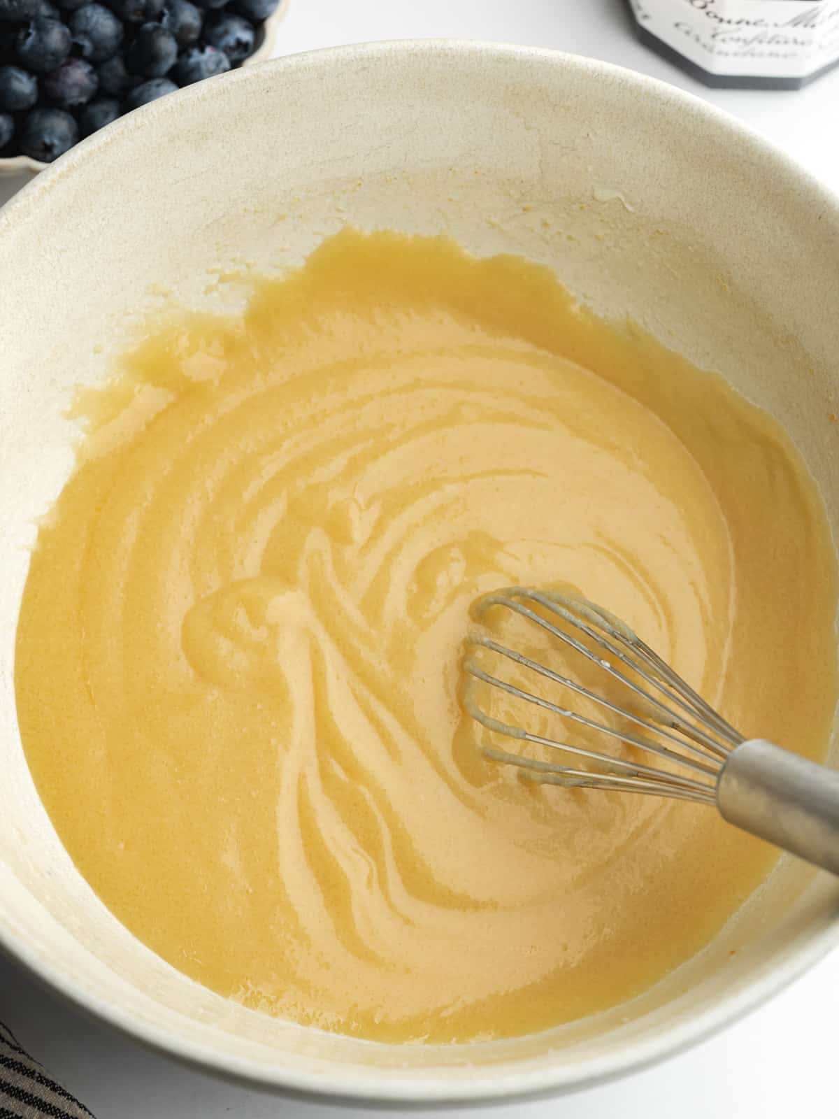 sugar, olive oil, yogurt, and vanilla whisked in a large ceramic bowl.