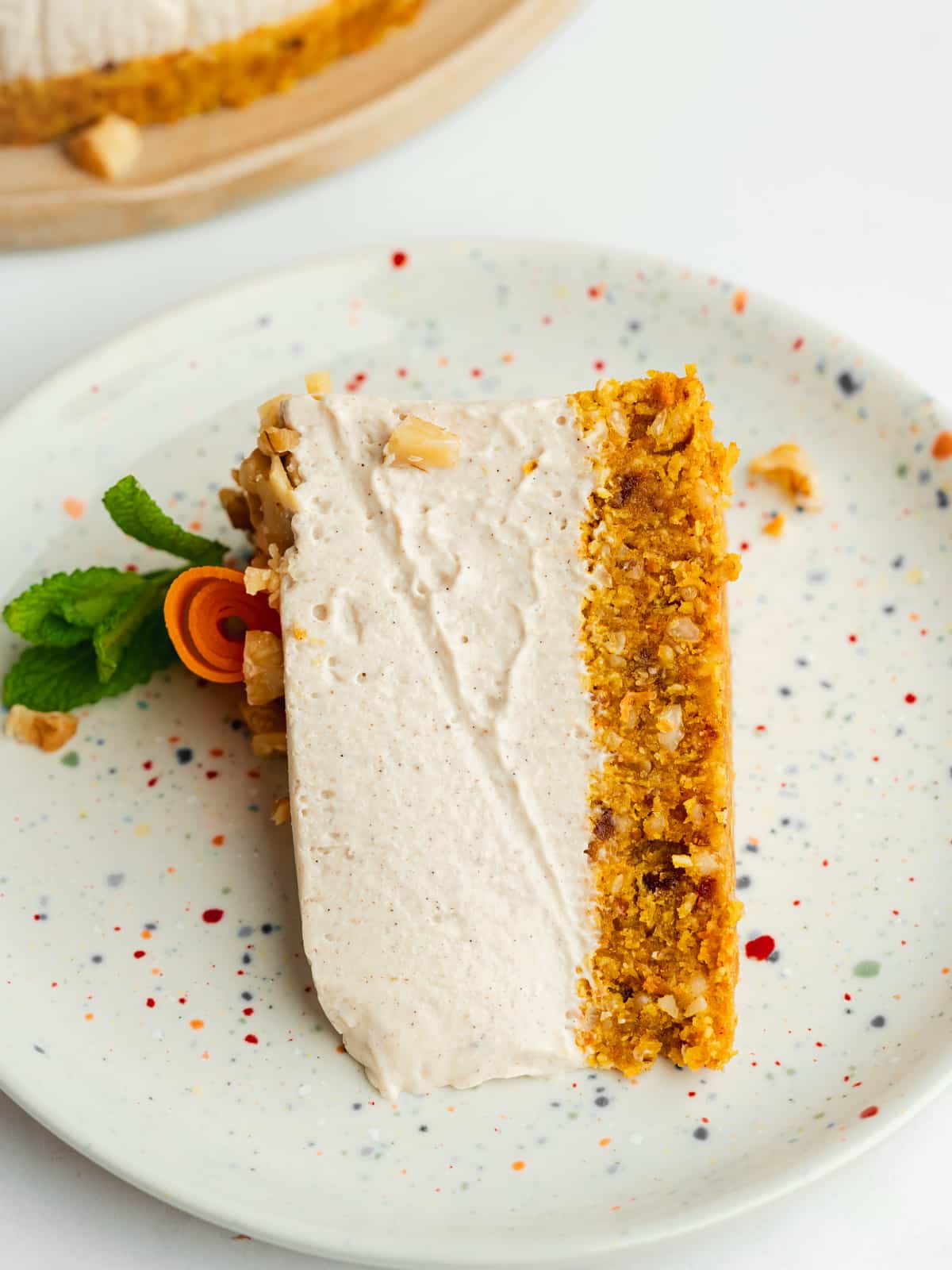 a slice of raw carrot cake cheesecake on a ceramic plate.