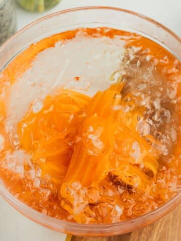 candied carrot slices in an ice bath to stop them cooking.