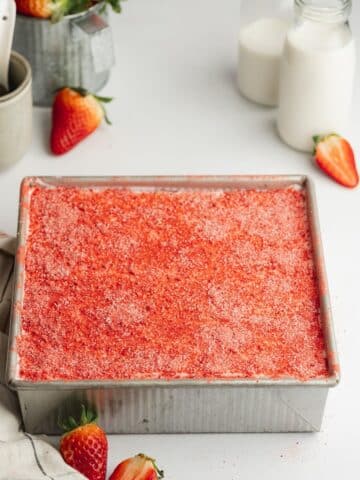 tres leches in a square pan with strawberry powder dusted on top.