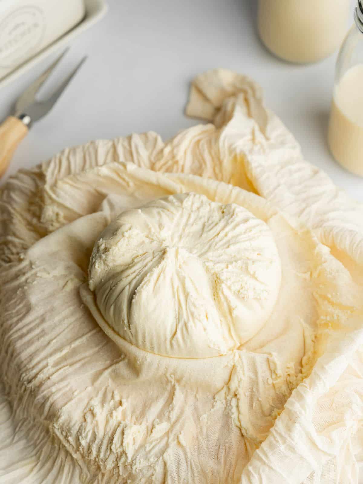 homemade macadamia cheese inside an opened up cheesecloth, it has formed a neat ball.