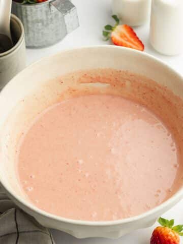 strawberry tres leches wet ingredients whisked in a ceramic bowl.