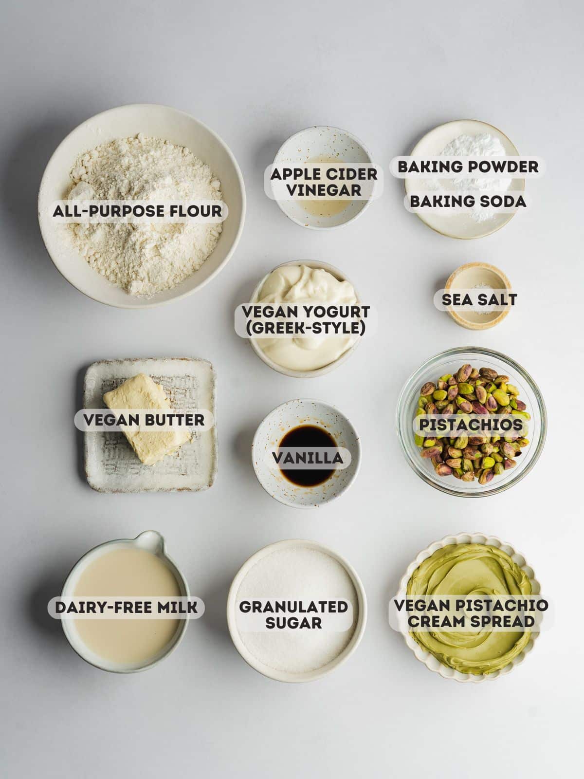 ingredients for vegan pistachio coffee cake measured out in bowls on a gray surface.