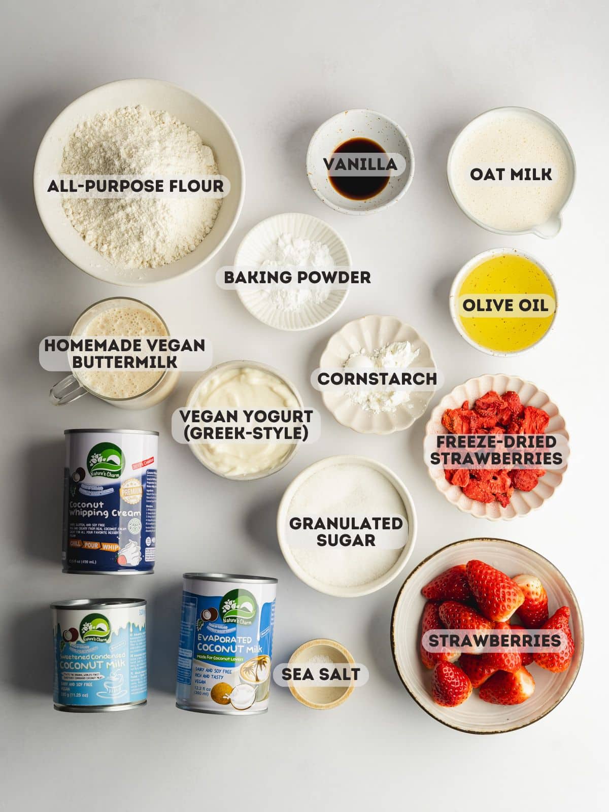 ingredients for strawberry tres leches measured out in bowls on a gray surface.