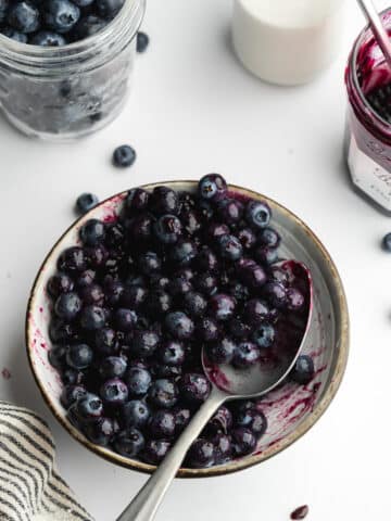 blueberries and blueberry jam mixed with a spoon in a small bowl.