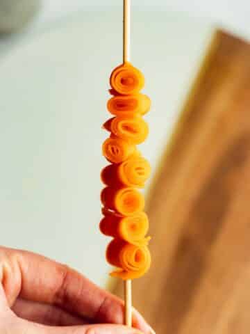 candied carrots rolled up on a bamboo skewer.
