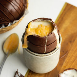 large creme egg cracked open with a spoon showing the gooey center.
