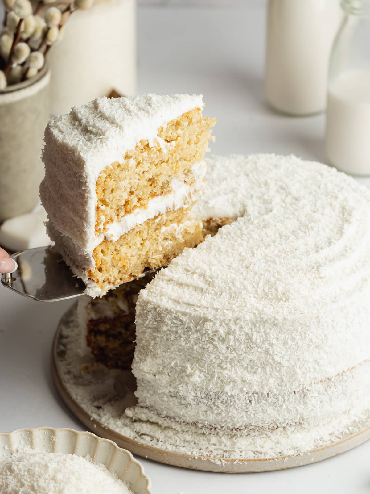coconut cake with a slice being lifted away showing the fluffy texture.