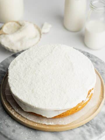 one layer of coconut cake topped with whipped cream and shredded coconut.