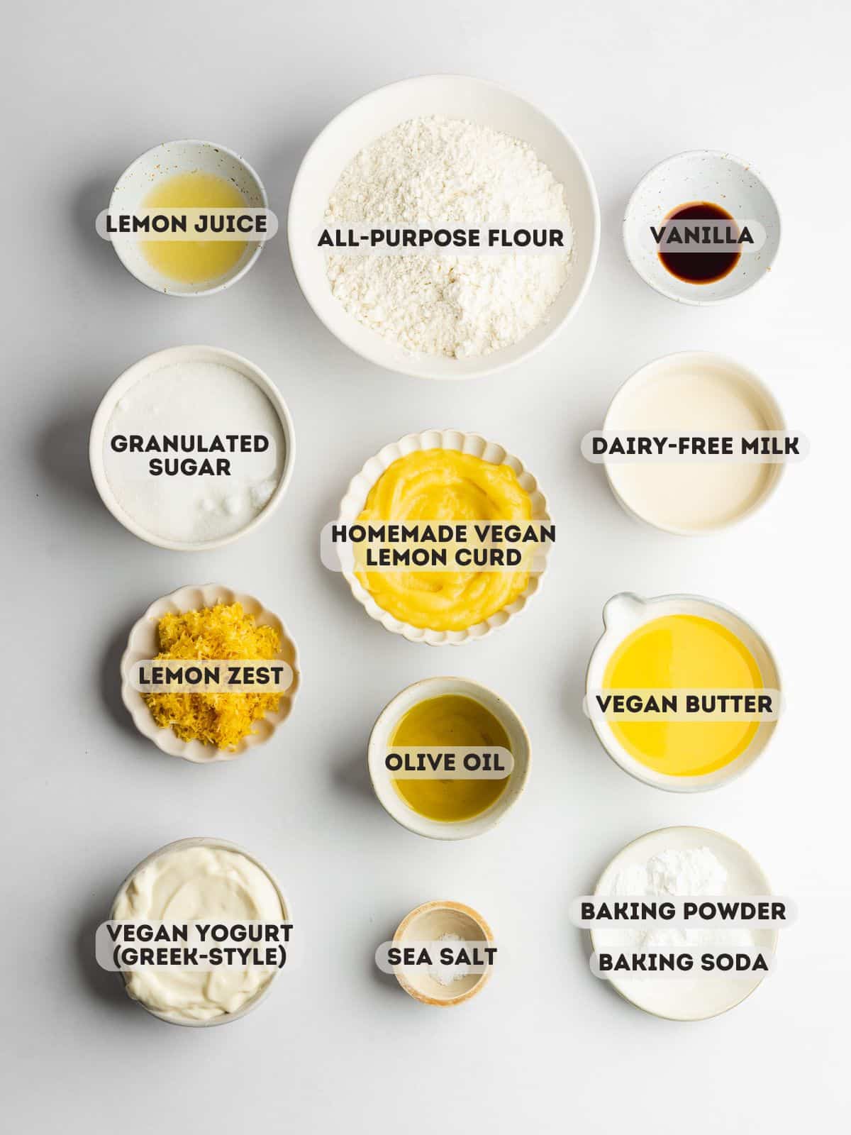 ingredients for vegan lemon curd cake measured out in bowls on a white surface.
