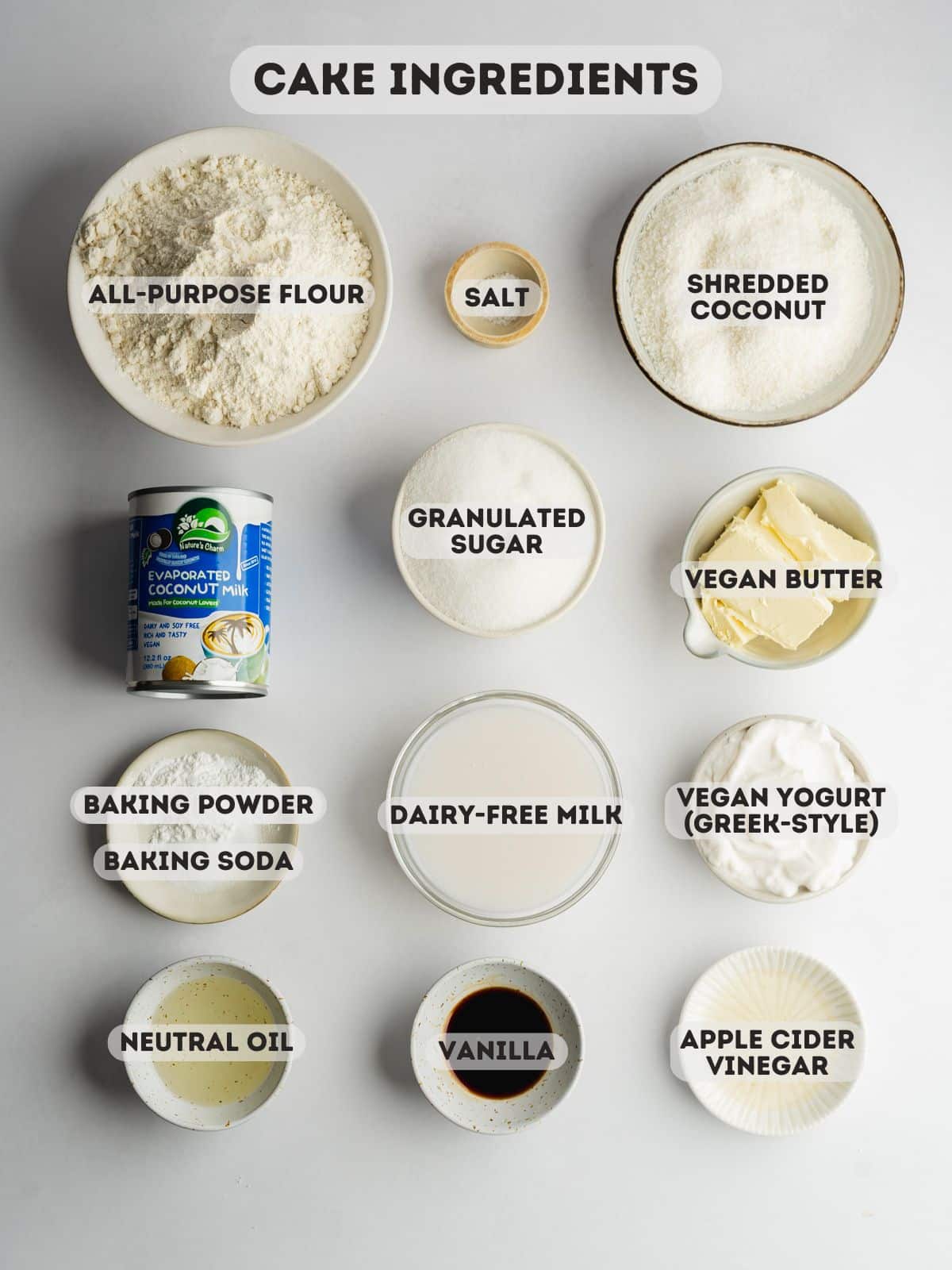 ingredients for coconut cake measured out in bowls on a gray surface.