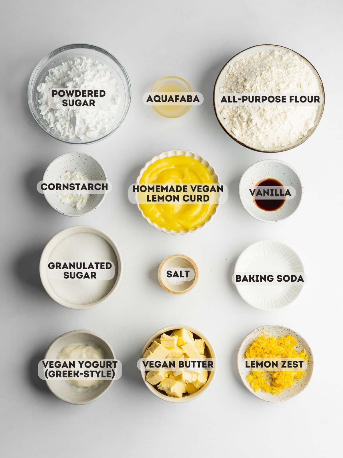 ingredients for lemon sugar cookies measured out in bowls on a gray surface.