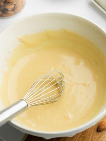 yogurt, oil, sugar, vanilla, and almond extract whisked in a ceramic bowl.