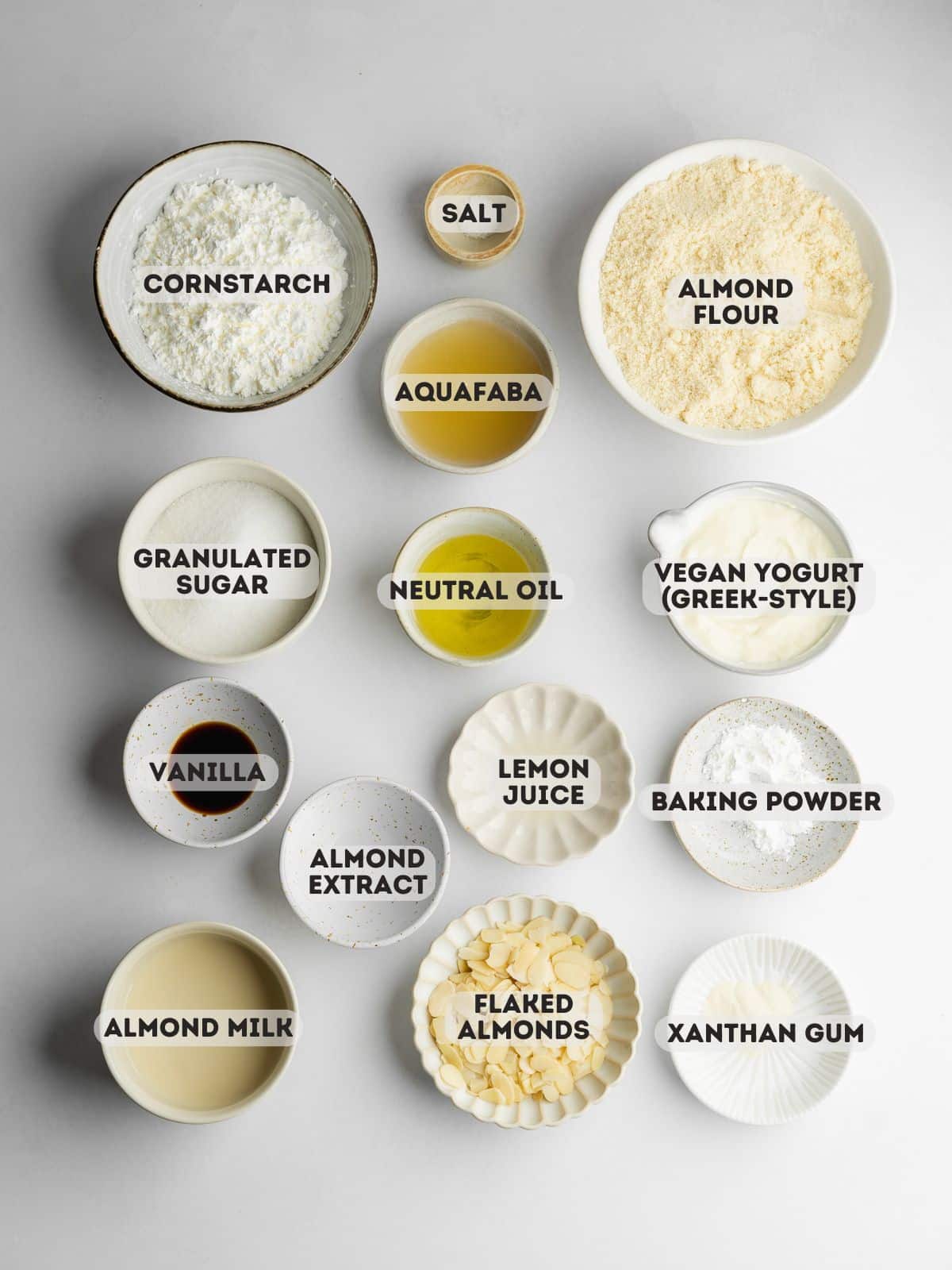 ingredients for almond cake measured out in bowls on a gray surface.