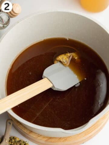 apple juice, sugar, vinegar, lemon juice, and chamomile tea simmering in a saucepan.