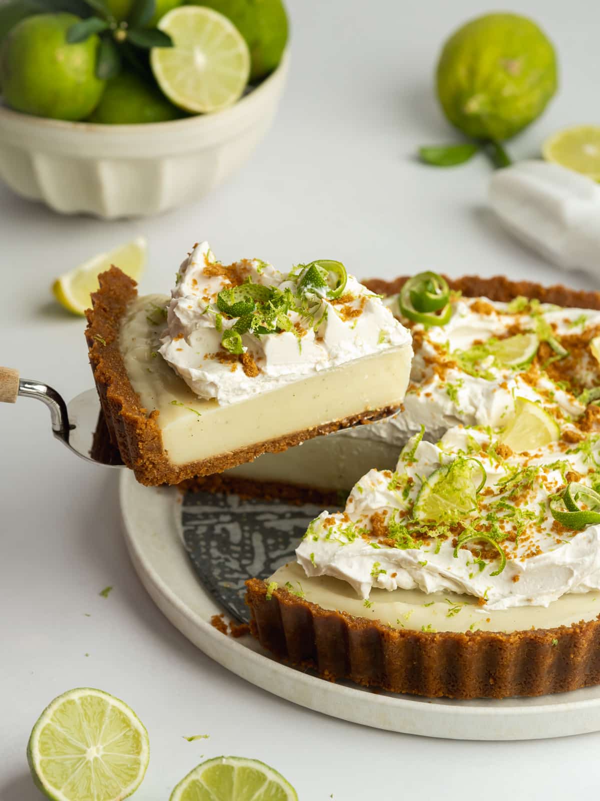 a key lime pie with a slice being lifted away on a cake slice.