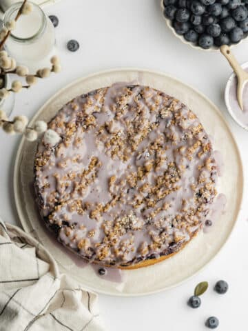 blueberry crumble cake with lilac colored icing drizzled on top.