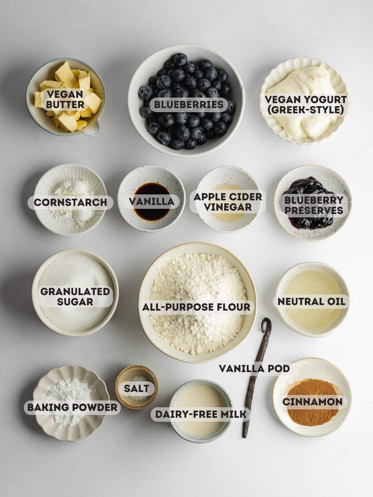 ingredients for blueberry crumb cake measured out in bowls on a gray surface.