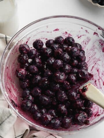 blueberries, jam , cornstarch, and sugar macerating in a clear bowl.