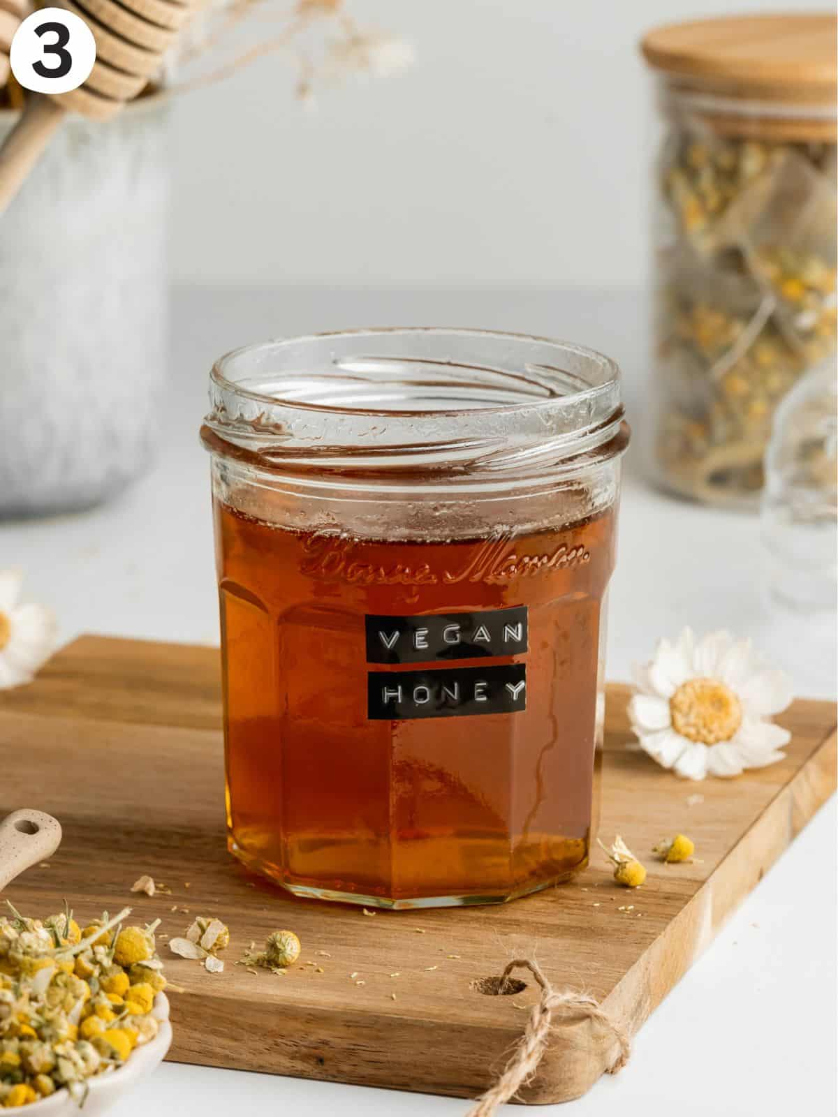 a jar labeled as vegan honey with apple honey on a wooden cutting board.