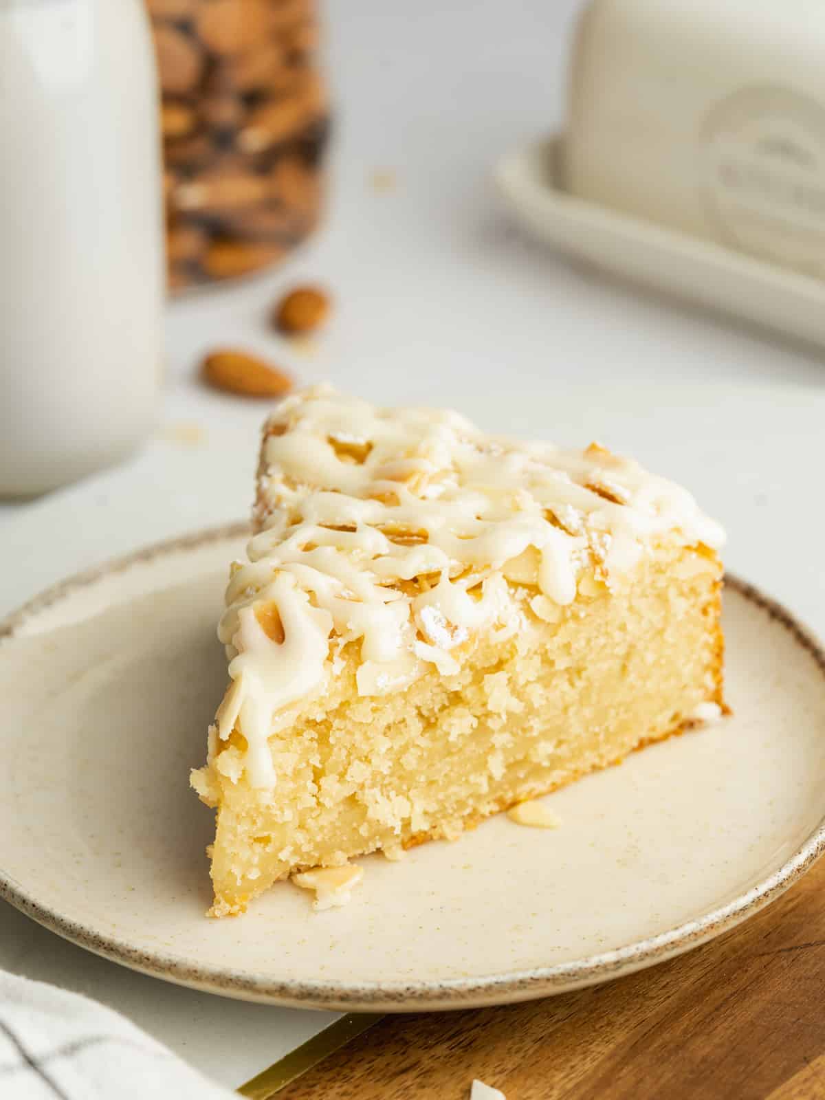 a fluffy slice of almond cake on a ceramic plate.