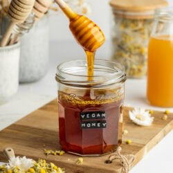 a jar of plant-based honey with some drizzling from a honey wand.