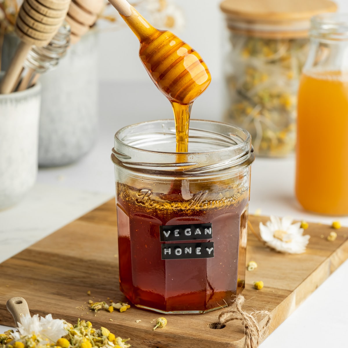 a jar of plant-based honey with some drizzling from a honey wand.