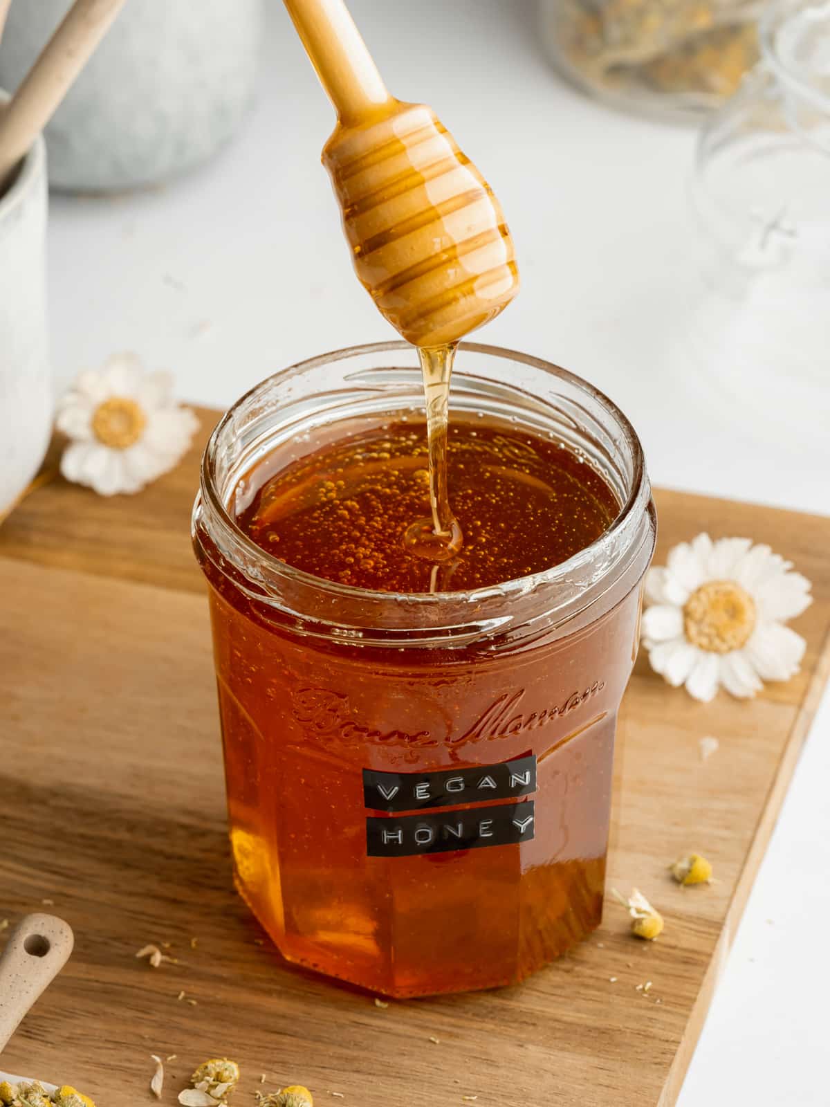 homemade vegan honey in a jar with a wooden honey stick.