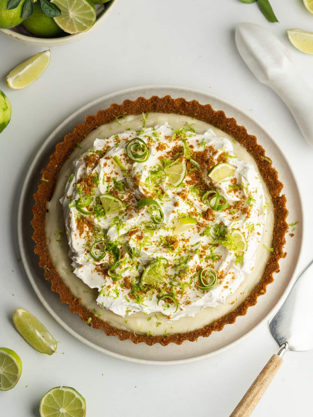 key lime pie topped with whipped coconut cream, crushed biscoff cookies, and freshly grated lime zest.