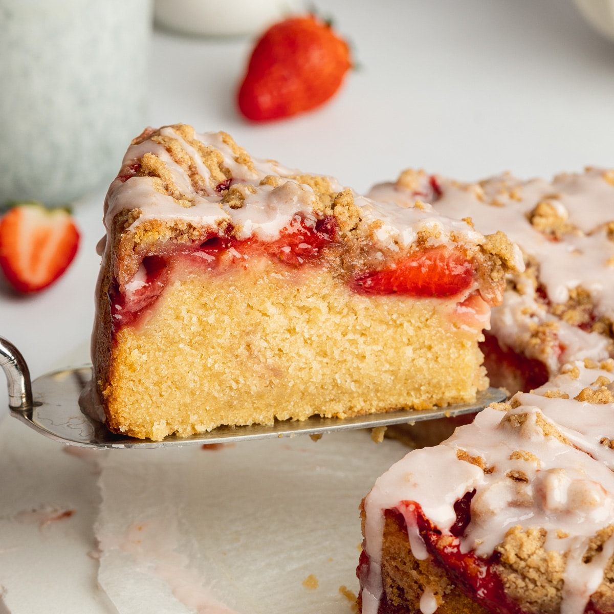 a slice of strawberry crumb cake being lifted away on a cake slice.