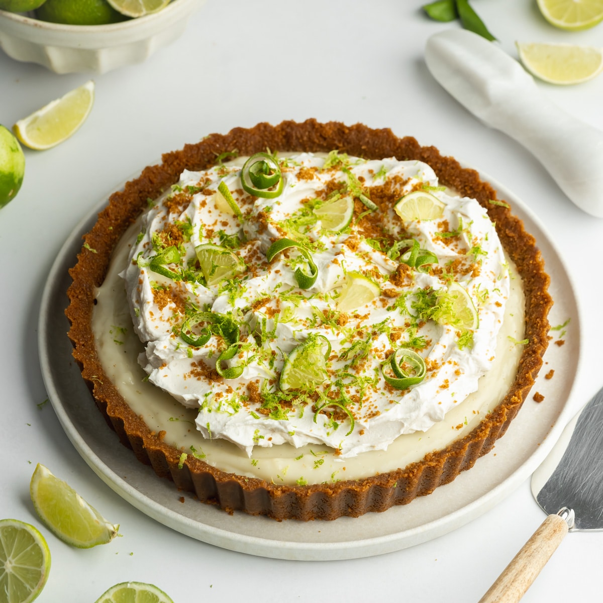 key lime pie with a cookie crust and whipped coconut cream, crushed cookies, and freshly grated lime zest on top.