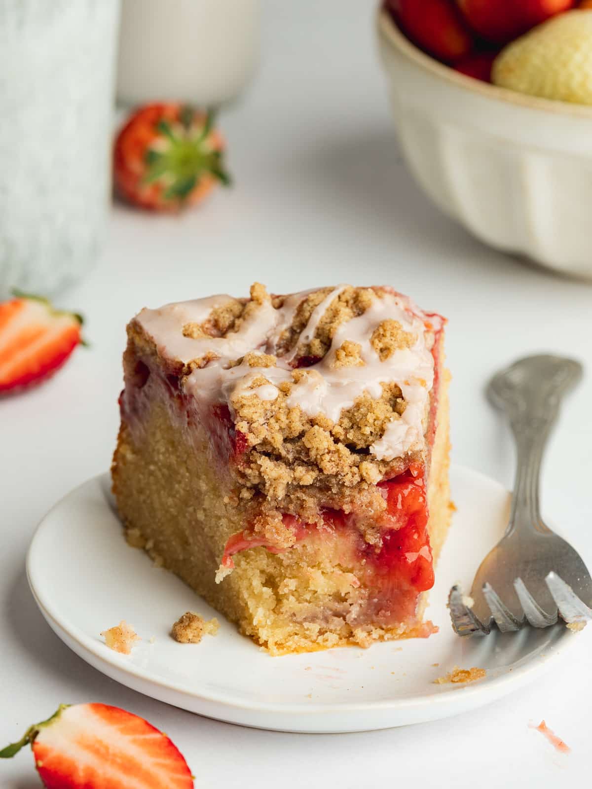 a slice of strawberry coffee cake with strawberry glaze and a piece eaten from it.