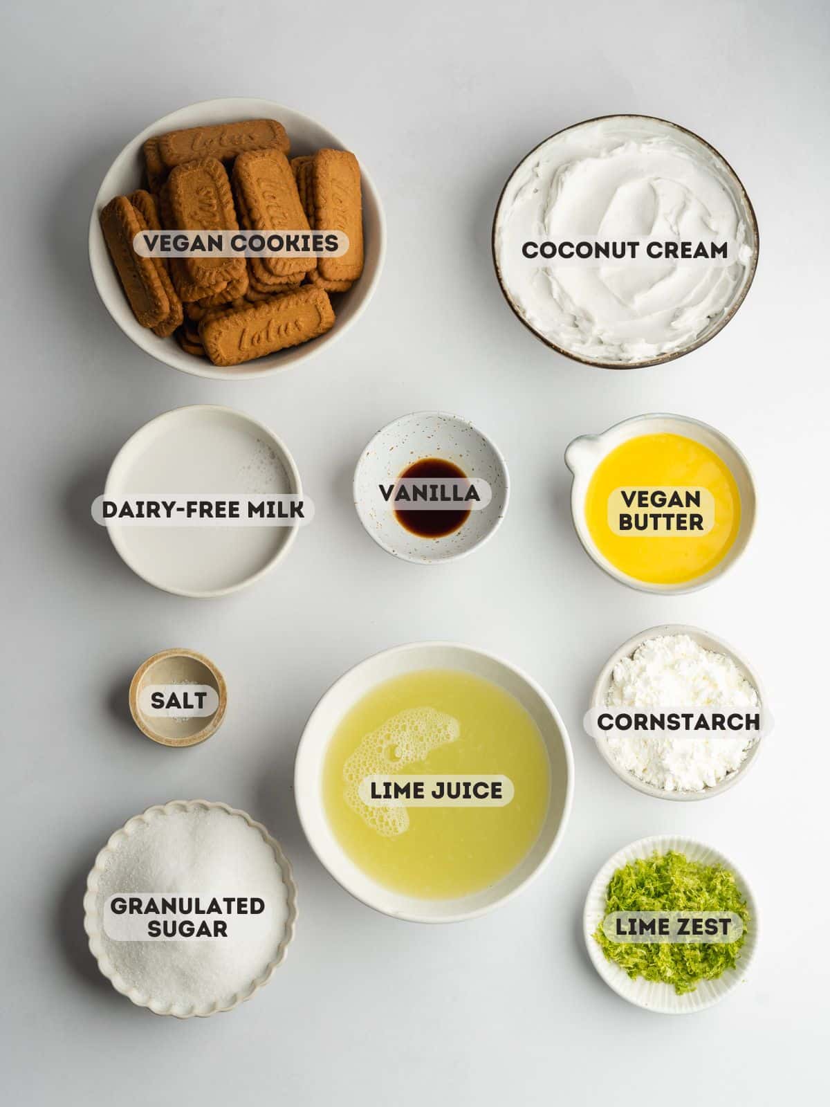 ingredients for vegan key lime pie measured out in bowls on a gray surface.