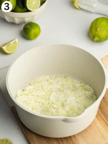 sugar with fresh lime zest rubbed into it in a white saucepan.