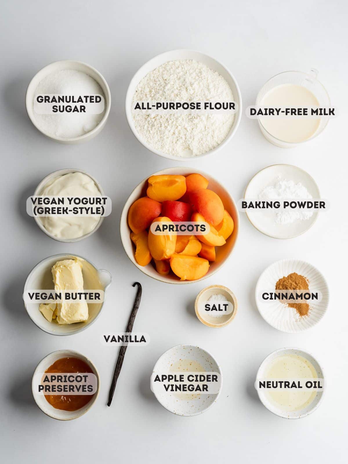 ingredients for apricot crumb cake measured out in bowls on a gray surface.