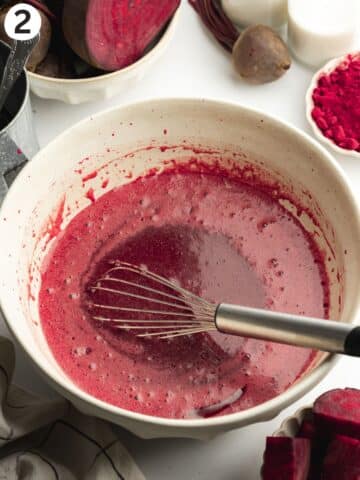 beetroot puree whisked into sugar and wet ingredients for beetroot cake in a large ceramic bowl.