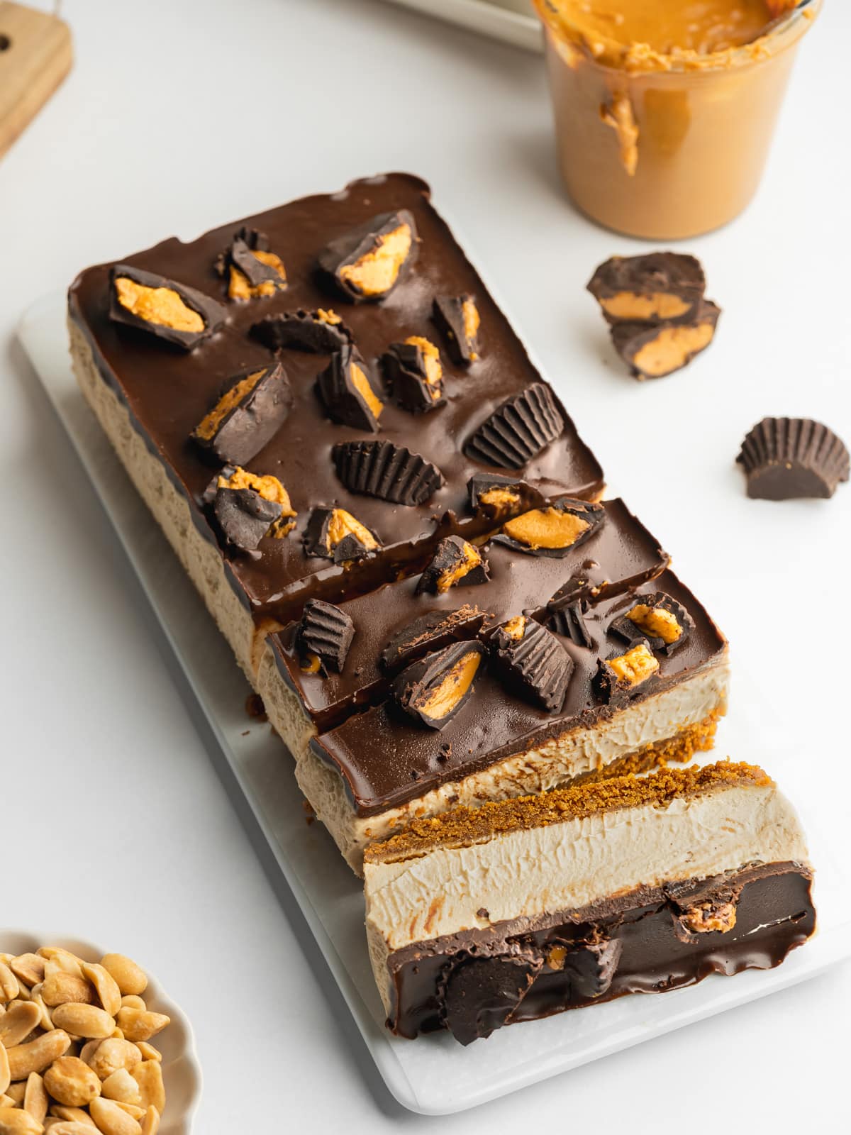 peanut butter cheesecake bars topped with chocolate ganache and mini peanut butter cups.