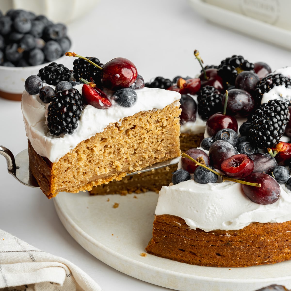 a slice of date cake topped with whipped coconut cream and fresh berries.